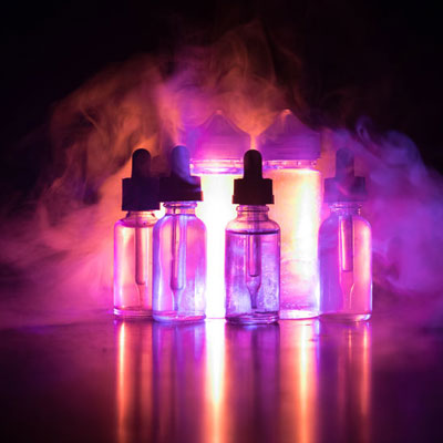 Five glass dropper bottles with purple and orange lighting in a smoky, dark background.